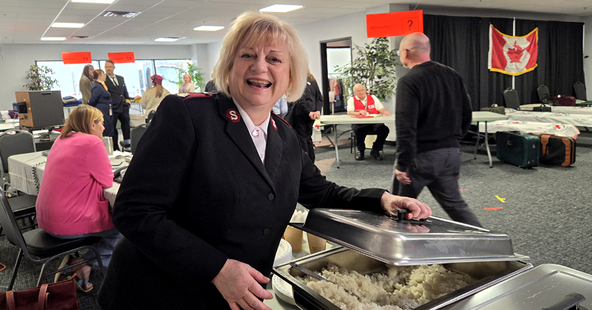 A Salvation Army officer stands by a buffet table smiling